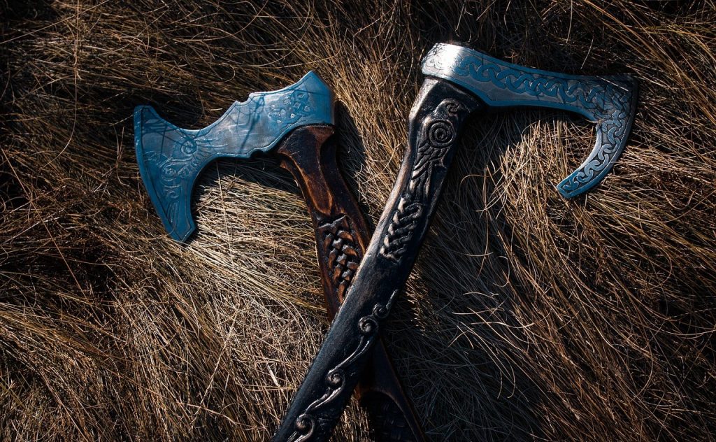 Two crossed Viking axes resting on a bed of hay, representing strength and historical symbolism of the viking heritage.